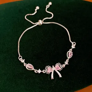 Dettaglio di un bracciale in argento con fiocco e zirconi rosa a forma di cuore e goccia