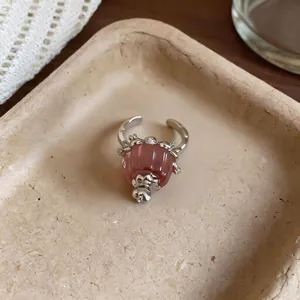 Detail of a silver open ring with a pink resin pudding charm and zircon accents.