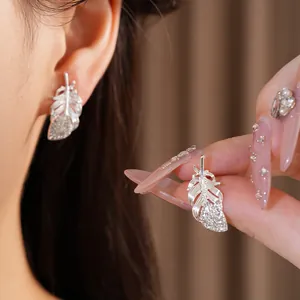 Primer plano de elegantes pendientes de plata en forma de pluma con pedrería