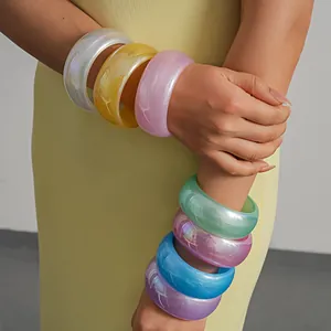 Detailed macro view of stacked iridescent resin bangles featuring vibrant dopamine colors
