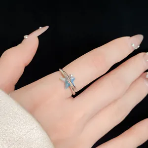 Primo piano di un delicato anello a stella minimalista in argento con gemma al dito.
