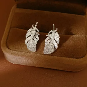 Primer plano de elegantes pendientes de pluma plateada con diamantes de imitación brillantes