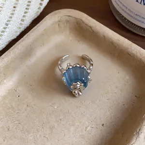 Close-up detail view of a blue translucent resin pudding-shaped ring with sparkling zircon accents