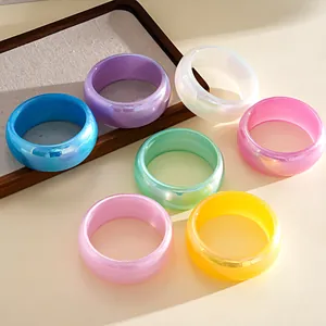 Set of colorful iridescent resin round bangles in dopamine style displayed on a tray.