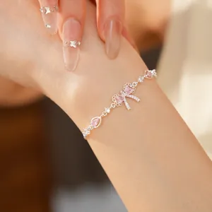Delicato bracciale in argento con un ciondolo a fiocco in zircone rosa sul polso di una modella