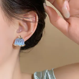 Detail of a Korean style blue resin pudding earring worn by a model on her ear