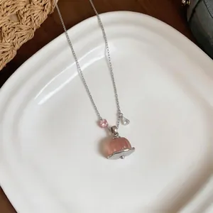Macro detail of pink resin pudding pendant with sparkling zircon on silver chain