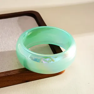 Macro detail of a mint green iridescent resin bangle with colorful shimmer and smudge pattern