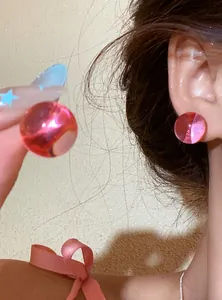 Close-up detail of vibrant pink translucent round ball stud earrings shown on model ear