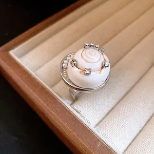 Bague coquillage bohème avec strass et perles dans un écrin à bijoux en velours.