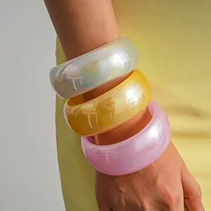 Macro view of three colorful iridescent resin bangles featuring a glossy pearlescent finish