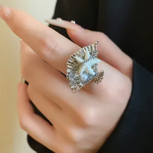 Gros plan d'une bague ouverte bohème en argent avec coquillage, étoile de mer et perles.