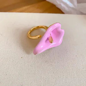 Dettaglio ravvicinato di un anello aperto in smalto rosa a forma di calla dorata