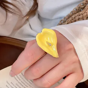 Dettaglio ravvicinato di un anello aperto in smalto calla lily giallo indossato sulla mano