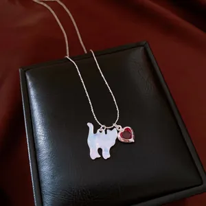Vue détaillée du collier argenté avec pendentif chat et cœur rouge sur une boîte à bijoux