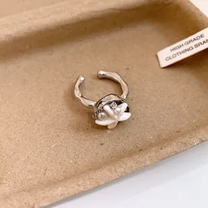 Détail macro d'une bague ouverte en forme de coquillage argenté avec perle et strass