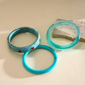 Detail of three resin bangles featuring marbled textures and colorful rhinestone accents