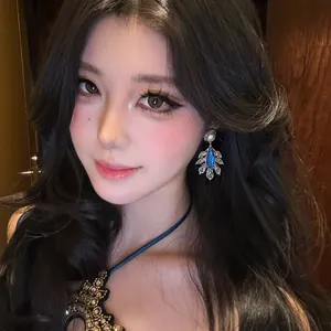 Detailed view of retro court style feather pearl earrings worn by an elegant model