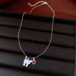 Détail des pendentifs chat et cœur rouge sur un collier argenté réglable