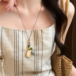 Detailed shot of a handcrafted forest style acorn pendant necklace worn with a linen dress