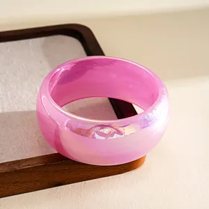 Detailed macro view of a pink iridescent resin bangle featuring unique swirling colorful textures