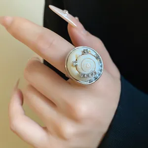 Gros plan d'une bague bohème en métal avec coquillage, perles et strass étincelants