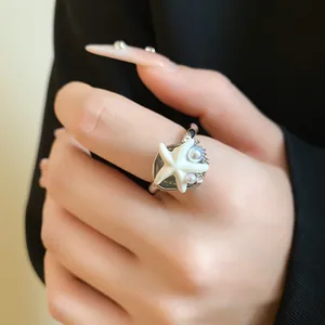 Détail d'une bague étoile de mer de style bohème avec perle et cristaux sur une main
