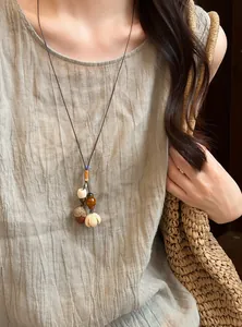 Detail of a handmade forest-style acorn necklace with wooden beads and woven rope cord.