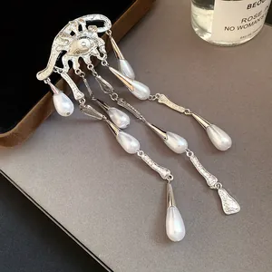 Close-up detail of an elegant silver eye brooch featuring long pearl waterdrop tassels.
