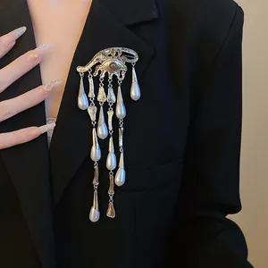 Detailed view of an ornate eye-shaped brooch with cascading pearl tassels on a blazer.