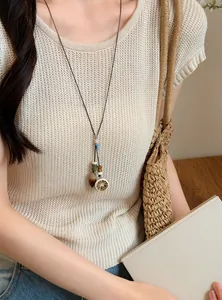 Close-up detail of a handmade Mori style long necklace with acorn and lemon pendants