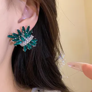 Detalle de primer plano de un lujoso pendiente de botón verde esmeralda con forma de fuego artificial