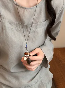 Close-up of handmade Mori-style long necklace with botanical acorn pod and wood beads