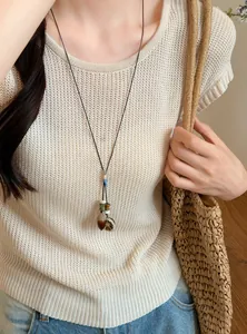 Detailed view of forest style acorn and lemon slice pendant necklace worn with knitwear