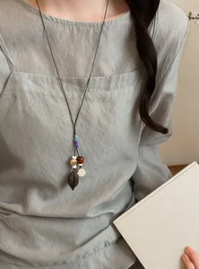 Detail view of handmade acorn pendant necklace worn on a light green linen shirt