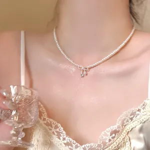 Detailed shot of an elegant pearl bow necklace with a shimmering zircon pendant on the neck