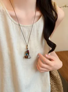 Close-up detail of a handmade forest style acorn necklace worn on a natural linen top