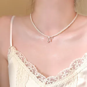 Elegant pearl choker necklace with a sparkling bow and zircon pendant in close-up detail.