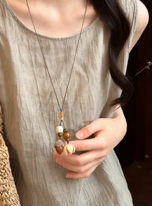 Close-up of a forest-style handmade acorn necklace on a textured linen dress