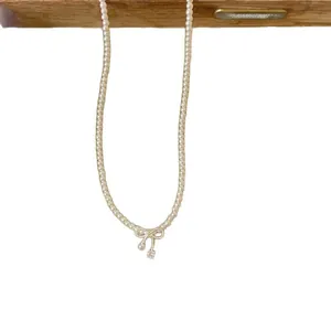 Elegant pearl choker necklace featuring a bow pendant with a clear zircon drop.