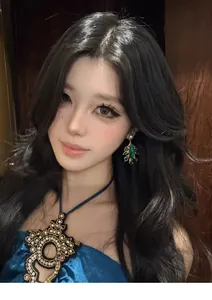 Close-up of model wearing retro court-style earrings with green gems and pearls.