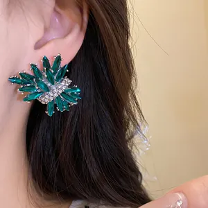 Primer plano de pendientes elegantes en forma de fuegos artificiales con strass verde