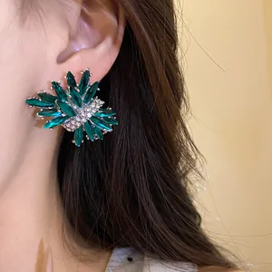 Primer plano de elegante pendiente de botón esmeralda con cristales brillantes en la oreja
