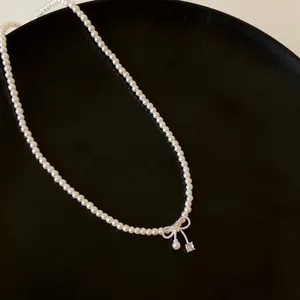 Elegant pearl necklace featuring a bow-shaped zircon pendant on a dark minimalist background