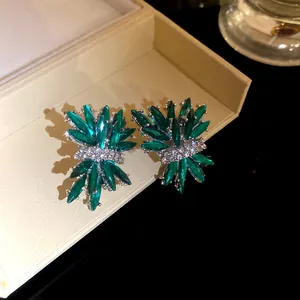 Detalle de pendientes de cristal verde esmeralda con forma de fuegos artificiales