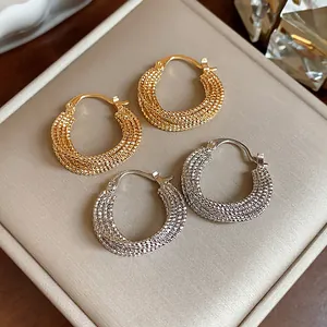 Detail view of 18k gold and silver plated textured hoop earrings on jewelry box