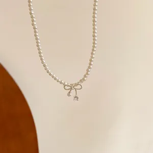 Detail view of a refined pearl necklace with a sparkling zircon-studded bow pendant