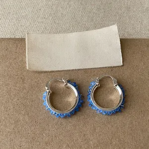 Nahaufnahme von eleganten blauen facettierten Glasperlen an silbernen Creolen.