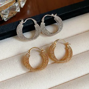 Detail shot of textured 18k gold and silver plated round hoop earrings on velvet