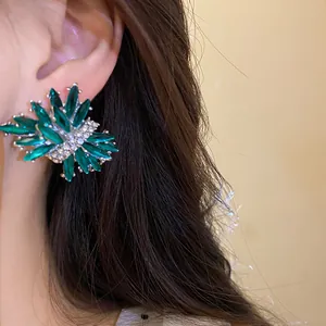 Primer plano de elegantes pendientes de fuegos artificiales con diamantes verdes